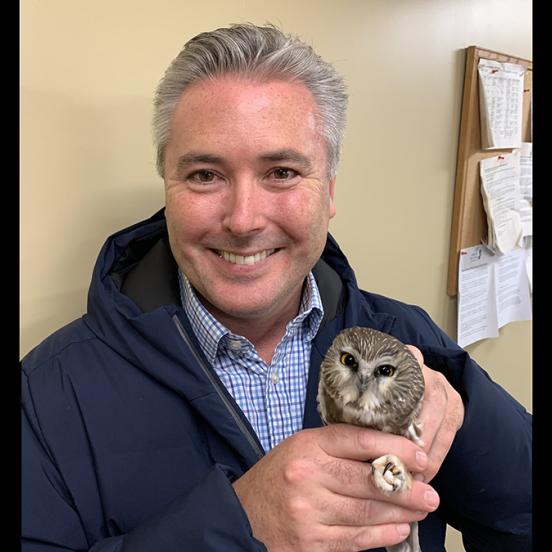 Rider alumnus Mark Bean poses holding a small owl. 