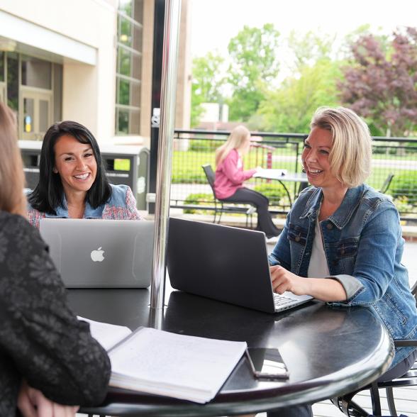 Graduate students working together at a table outside on campus