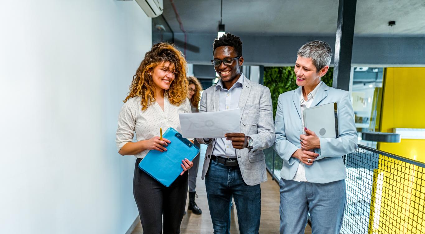 Smiling man and two women at work looking at a report together