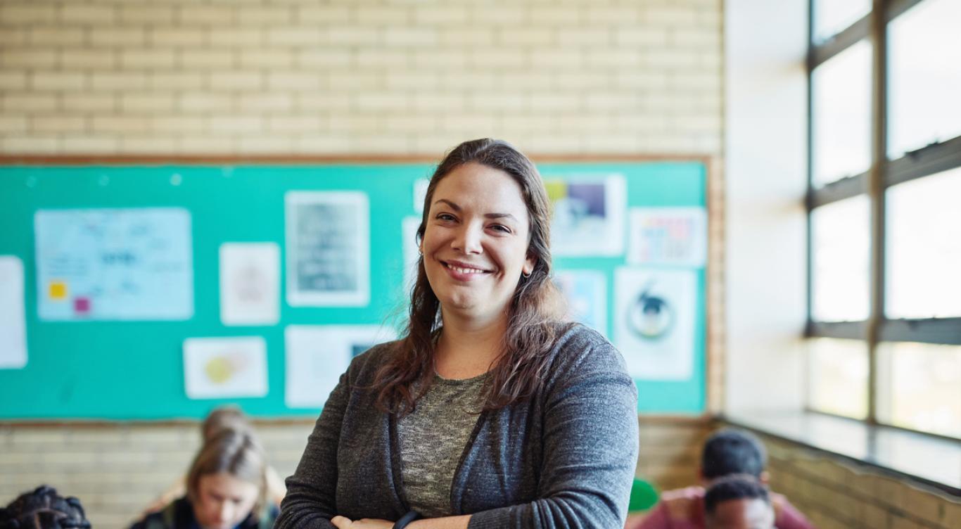 Teacher smiling in front of children in classroom