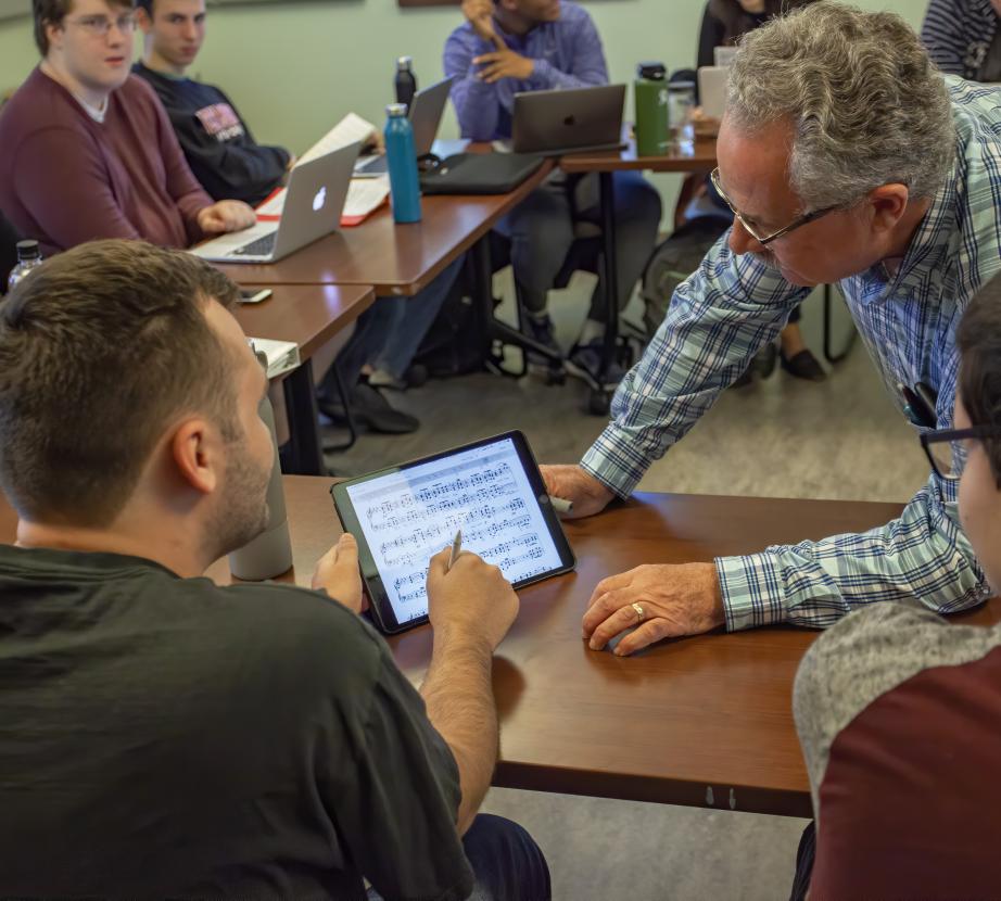 Male faculty member helps student on ipad