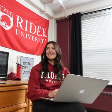Rider student sits with laptop in residential hall