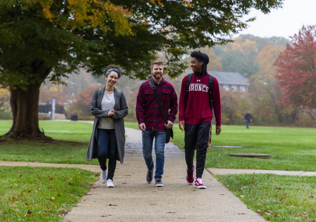 Three students walk on path in autumn