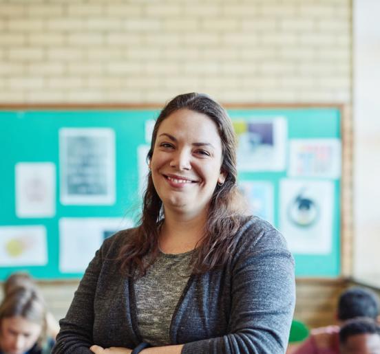 Teacher smiling in front of children in classroom